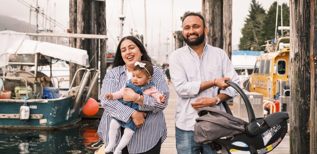 Man and his wife and child walk along a dock, smiling